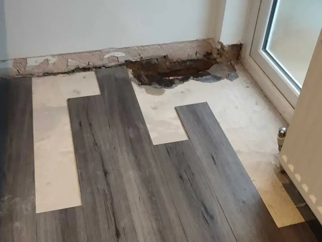 A kitchen laminate floor partly relaid, with the opening by the wall still showing