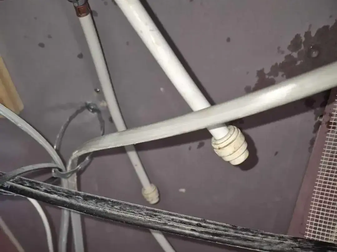 Old plastic pipes exposed inside a ceiling void