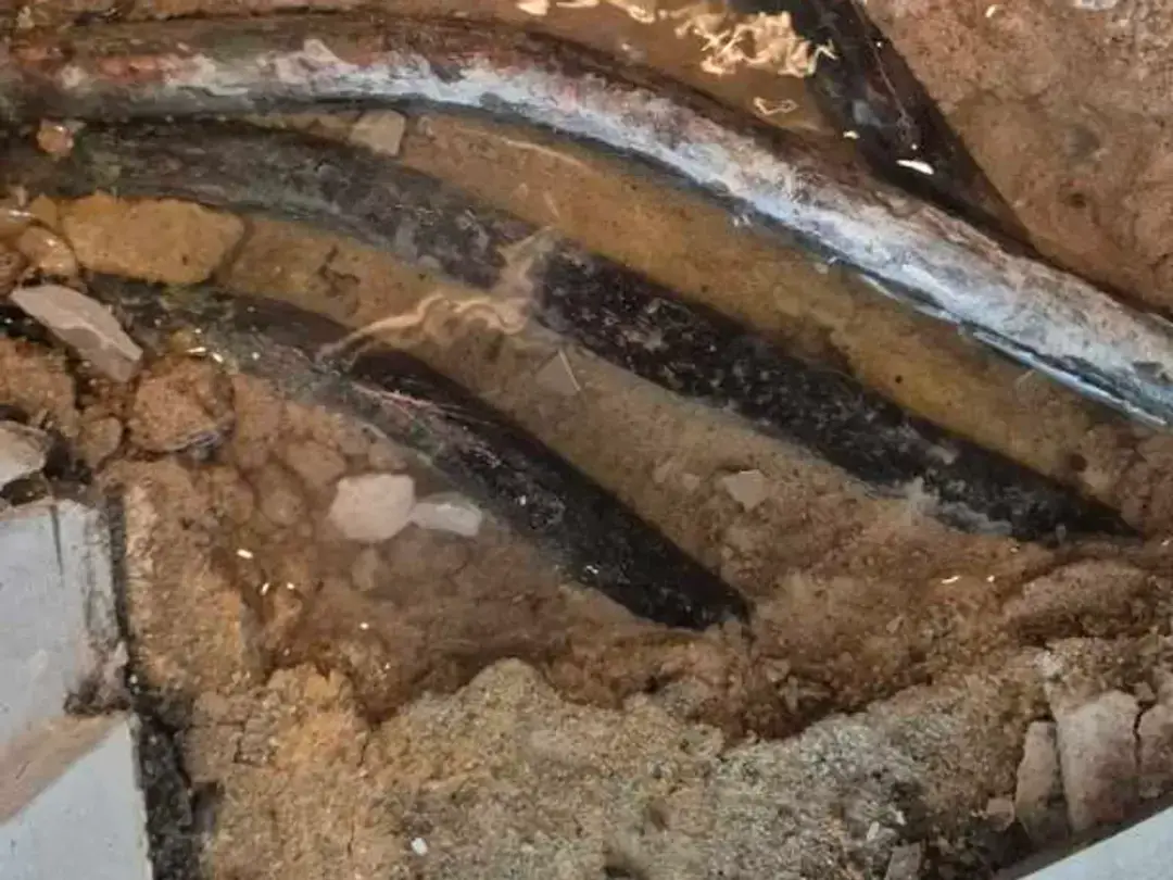 Copper pipes sitting in waterlogged screed in an opening under a tiled floor